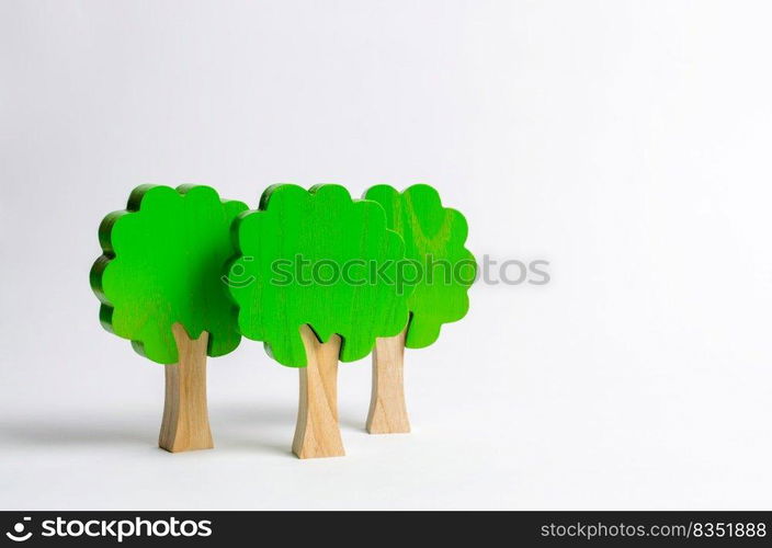 Three toy wooden figures of trees on a white background. Forest imitation. environmental conservation. Light planets. Family tree, a symbol of strength and wisdom. Illegal deforestation.