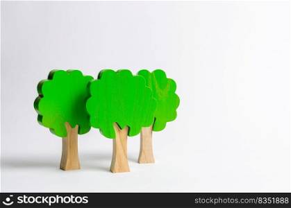 Three toy wooden figures of trees on a white background. Forest imitation. environmental conservation. Light planets. Family tree, a symbol of strength and wisdom. Illegal deforestation.