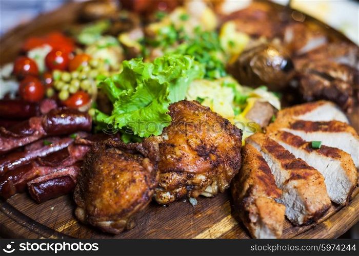 Three types of meat with lettuce and tomatoes lying on a wooden board