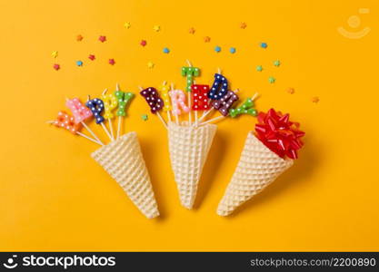 three waffle cones ribbon bow happy birthday text candles with sprinkles yellow backdrop