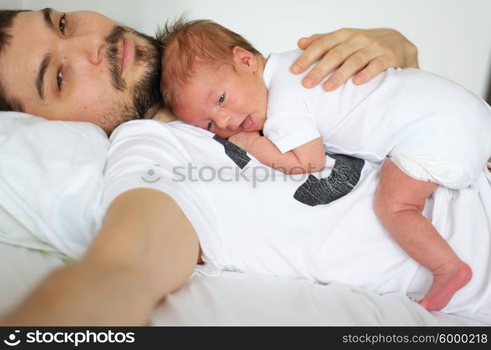 Three weeks old newborn with his father. Shallow depth of field.