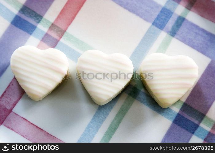 Three white chocolate hearts on a chequed background