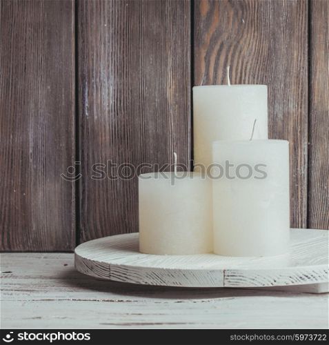 Three white Christmas candles mounted on a round stand. Christmas candles