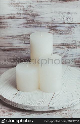 Three white Christmas candles mounted on a round stand. Christmas candles