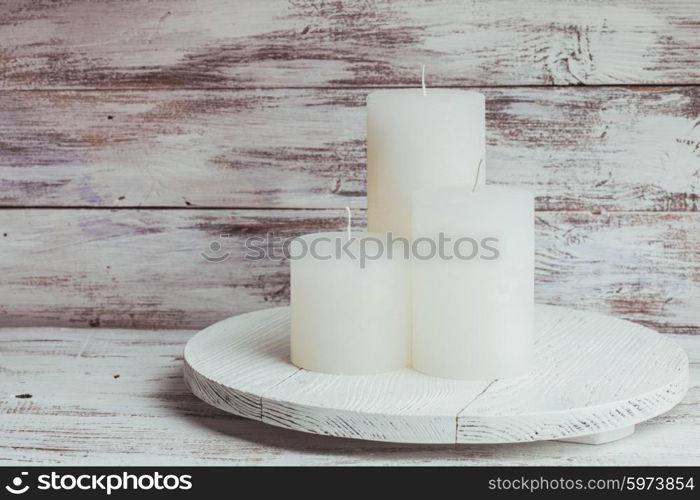 Three white Christmas candles mounted on a round stand. Christmas candles