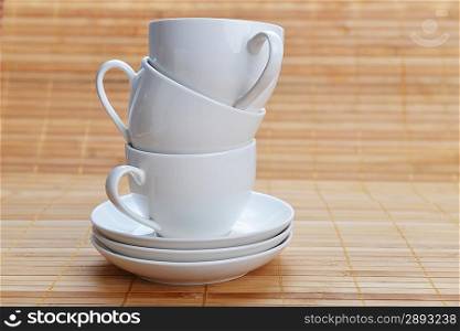 three white coffee cups with saucers on wooden background white
