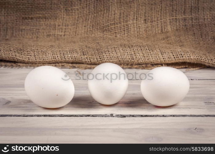Three white eggs on a old wooden table