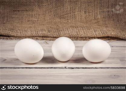Three white eggs on a old wooden table
