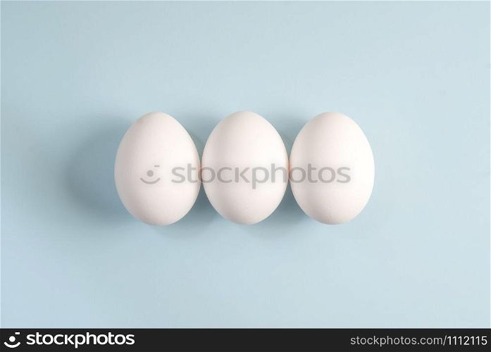 Three white eggs on blue background.