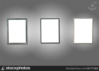 Three white isolated wooden frames on the gray wall