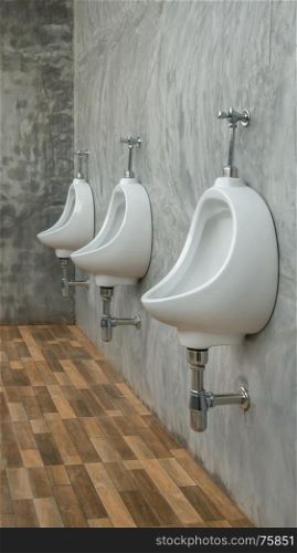 three white urinals men public toilet in restroom outdoors. three white urinals
