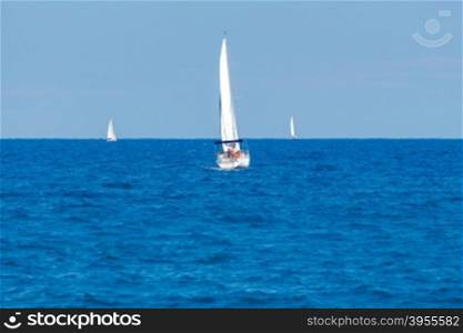 Three white yacht under sail in the sea in front of the beach of Barceloneta.. Barcelona. Sailboats in the bay.