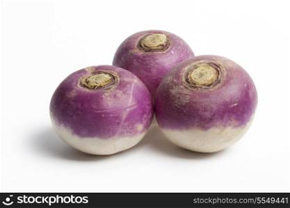 Three whole purple headed turnips on white background