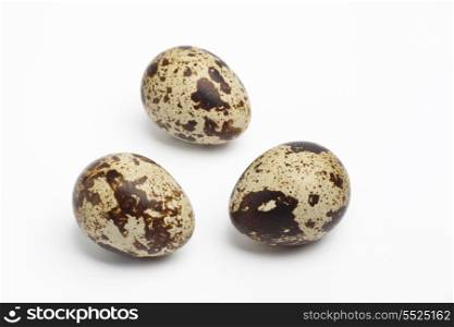 Three whole quail eggs on white background