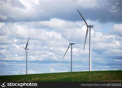Three wind turbines on a blue and cloudy sky. Sustainable energy.. Three wind turbines