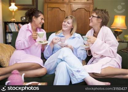 Three woman in night clothes sitting at home drinking tea
