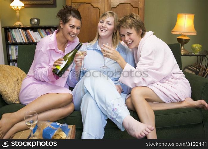 Three woman in night clothes sitting at home drinking wine