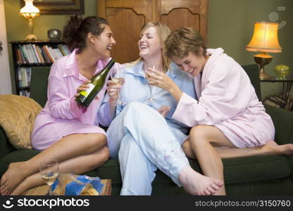 Three woman in night clothes sitting at home drinking wine