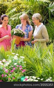 Three woman shopping potted flowers at garden centre green house