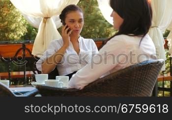 Three women at cafe, talking and drinking coffee