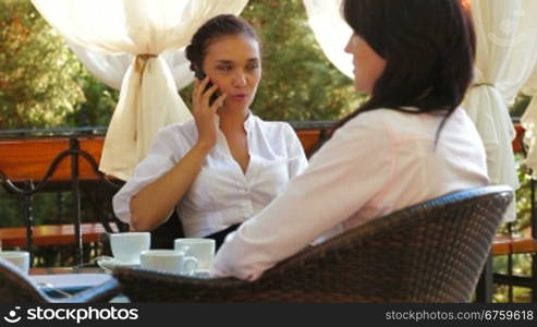 Three women at cafe, talking and drinking coffee