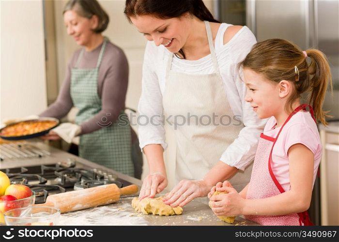Three women baking apple pies grandmother, mother and daughter