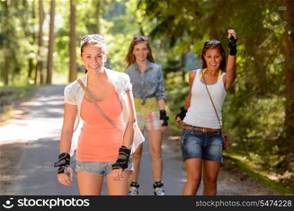Three women friends roller skating outdoors summer park