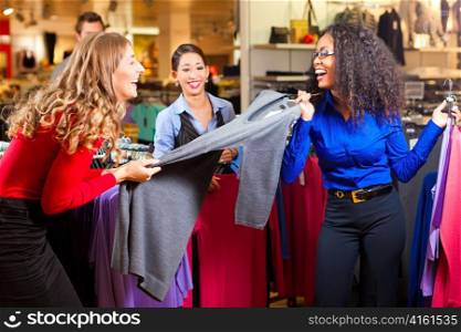 Three women in a shopping mall downtown looking for clothes