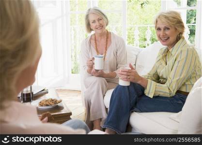 Three women in living room with coffee smiling