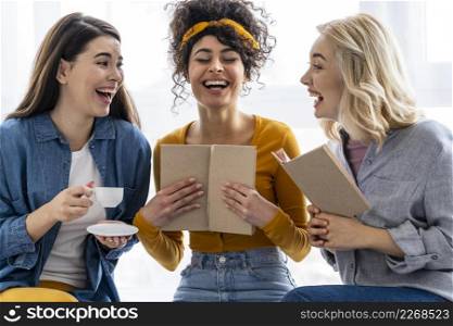 three women laughing together with book