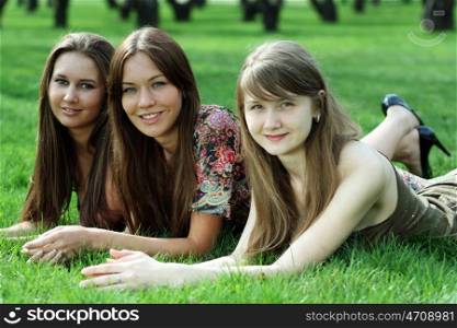 Three women lying on a green lawn