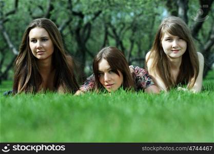 Three women lying on a green lawn
