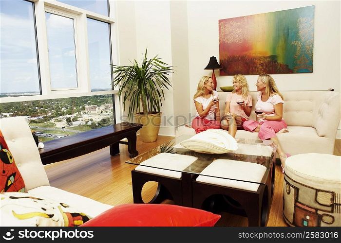 Three women sitting together and holding glasses of wine