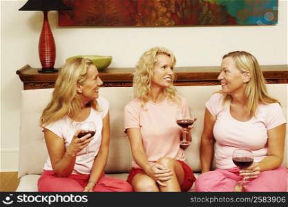Three women sitting together and holding glasses of wine