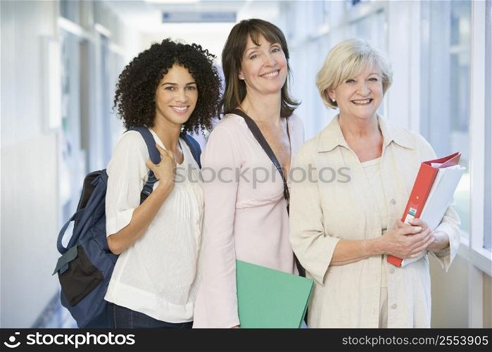 Three women standing in corridor with books (high key)