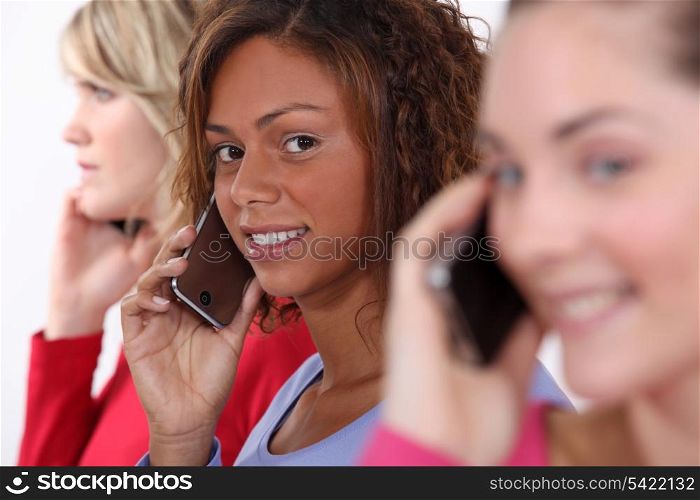 Three women using mobile telephones