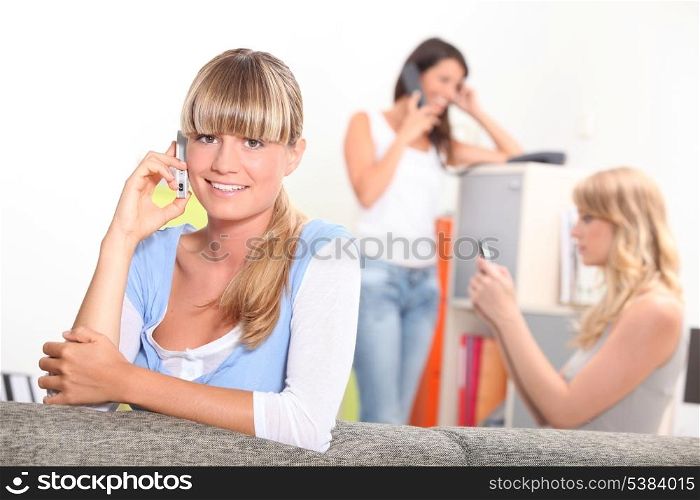 Three women using telephones at home