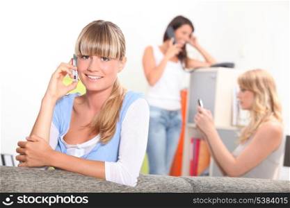 Three women using telephones at home
