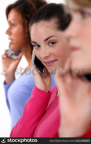 Three women using their mobile telephones