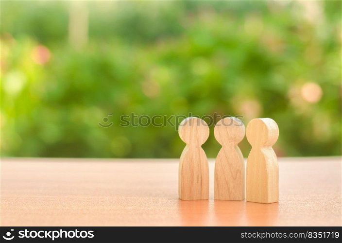 three wooden figures of people stand on the background of nature. Communication, meeting place. conduct a conversation. Discussion of cases and plans, society and community. Place for text.