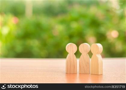 three wooden figures of people stand on the background of nature. Communication, meeting place. conduct a conversation. Discussion of cases and plans, society and community. Place for text.