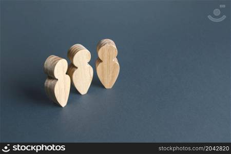 Three wooden human figurines on a gray background. Communication and discussion. Social Meeting. Assistance, cooperation and collaboration.