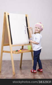 Three-year-old girl playing in the artist. Girl draws on the easel paints