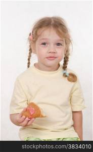 Three year old girl with pigtails and funny enthusiastically eating a bun