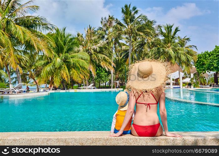 Three year old toddler boy in resort swimming pool with mother. Summer family vacation at Maldives.