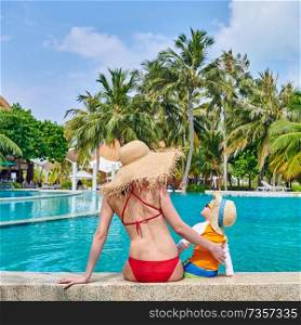 Three year old toddler boy in resort swimming pool with mother. Summer family vacation at Maldives.