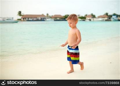 Three year old toddler boy on beach at dusk. Summer family vacation at Maldives.