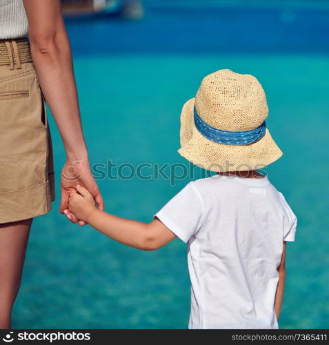 Three year old toddler boy on beach holding mother&rsquo;s hand. Summer family vacation at Maldives.