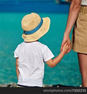 Three year old toddler boy on beach holding mother’s hand. Summer family vacation at Maldives.