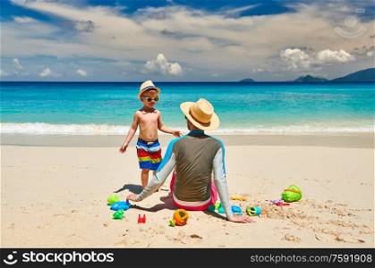 Three year old toddler boy on beach with father. Summer family vacation at at Seychelles, Mahe.